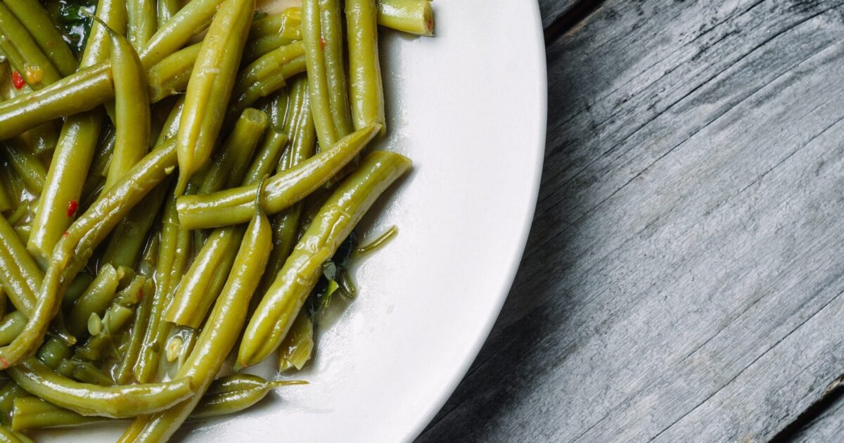 A high angle shot of boiled green beans in a white plate - perfect for an article about vegan food