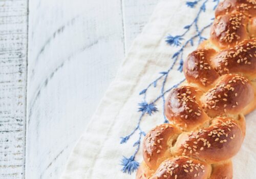 Challah bread. Sabbath kiddush ceremony composition. Freshly baked homemade braided challah bread for Shabbat and Holidays on white wooden background, Shabbat Shalom. Top view. Copy space.